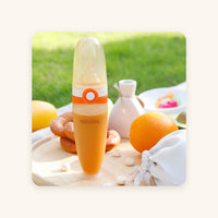 Nibbles silicone baby spoon feeder 120 ml filled with puree, on a picnic board with fruit